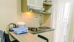 A compact kitchen with a sink, stove, and a kettle on the counter. - Comfort And Simply 2Br At Green Pramuka City Apartment (Jakarta)