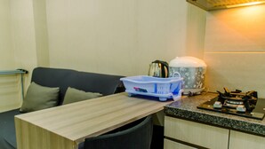 A compact kitchenette with a countertop, a kettle, a coffee maker, and a small stove. - Comfort And Simply 2Br At Green Pramuka City Apartment (Jakarta)