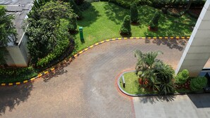 An aerial view of a landscaped area with a curved brick pathway, surrounded by greenery and a palm tree. - Good Deal and Comfy Studio West Vista Apartment (Jakarta)