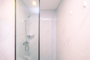 A modern shower with a glass door, a handheld showerhead, and a wall-mounted faucet. - Best Homey And Nice 1Br At Ciputra World 2 Apartment (Jakarta)