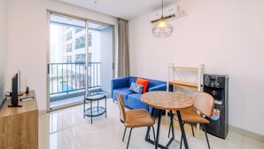 A modern living room with a sofa, chairs, a coffee table, a TV, and a water dispenser. - Best Homey And Nice 1Br At Ciputra World 2 Apartment (Jakarta)