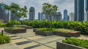 A rooftop garden with potted plants and a tiled walkway. - Best Homey And Nice 1Br At Ciputra World 2 Apartment (Jakarta)