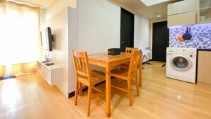 Una cocina compacta con una mesa y sillas de madera, una lavadora y un mueble pequeño.