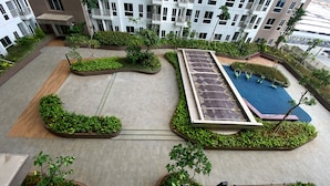A rooftop garden with a swimming pool, surrounded by greenery and modern buildings in the background.