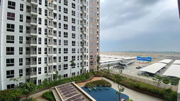 A high-rise building with multiple balconies, a swimming pool, and a parking area with a sign for Harvard and Cambridge.