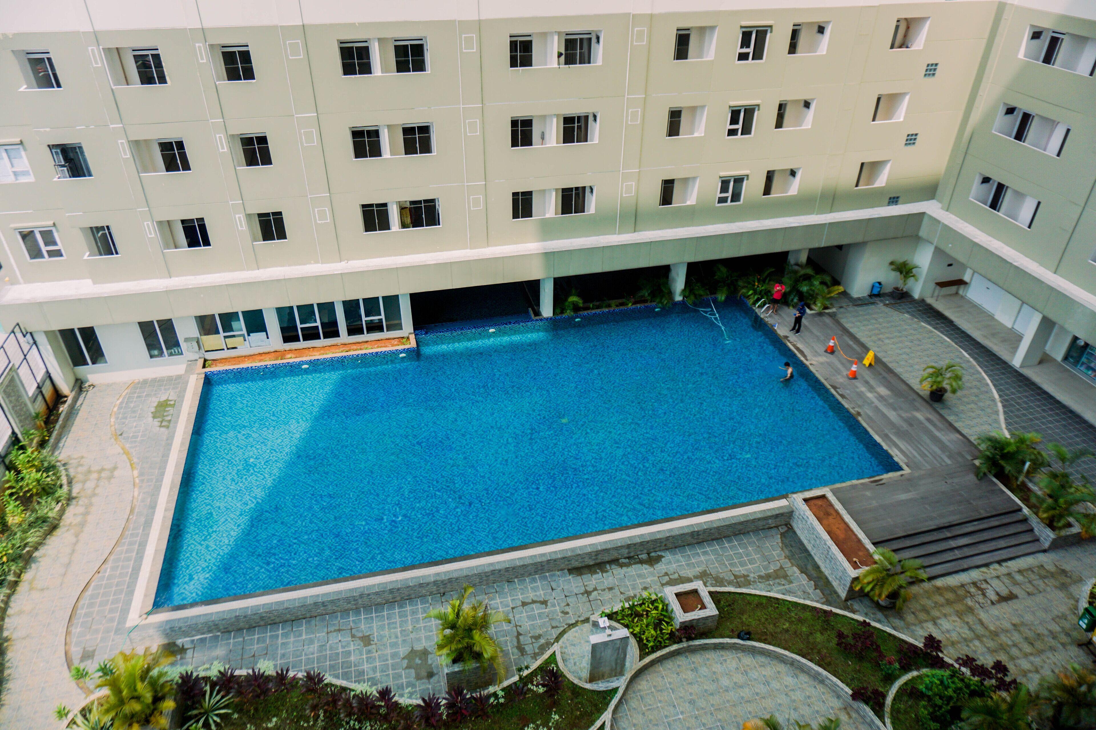 A large indoor swimming pool surrounded by a multi-story building with balconies.