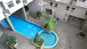 A rooftop pool area with a blue pool, surrounded by potted plants and a tiled floor. - Spacious Studio With Extra Room At Grand Asia Afrika Apartment (Bandung)