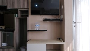 A modern kitchen with a built-in TV, a wooden countertop, and a water dispenser. - Spacious Studio With Extra Room At Grand Asia Afrika Apartment (Bandung)