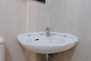 Un lavabo blanc, avec un robinet chromé, fixé sur un mur recouvert de carreaux.