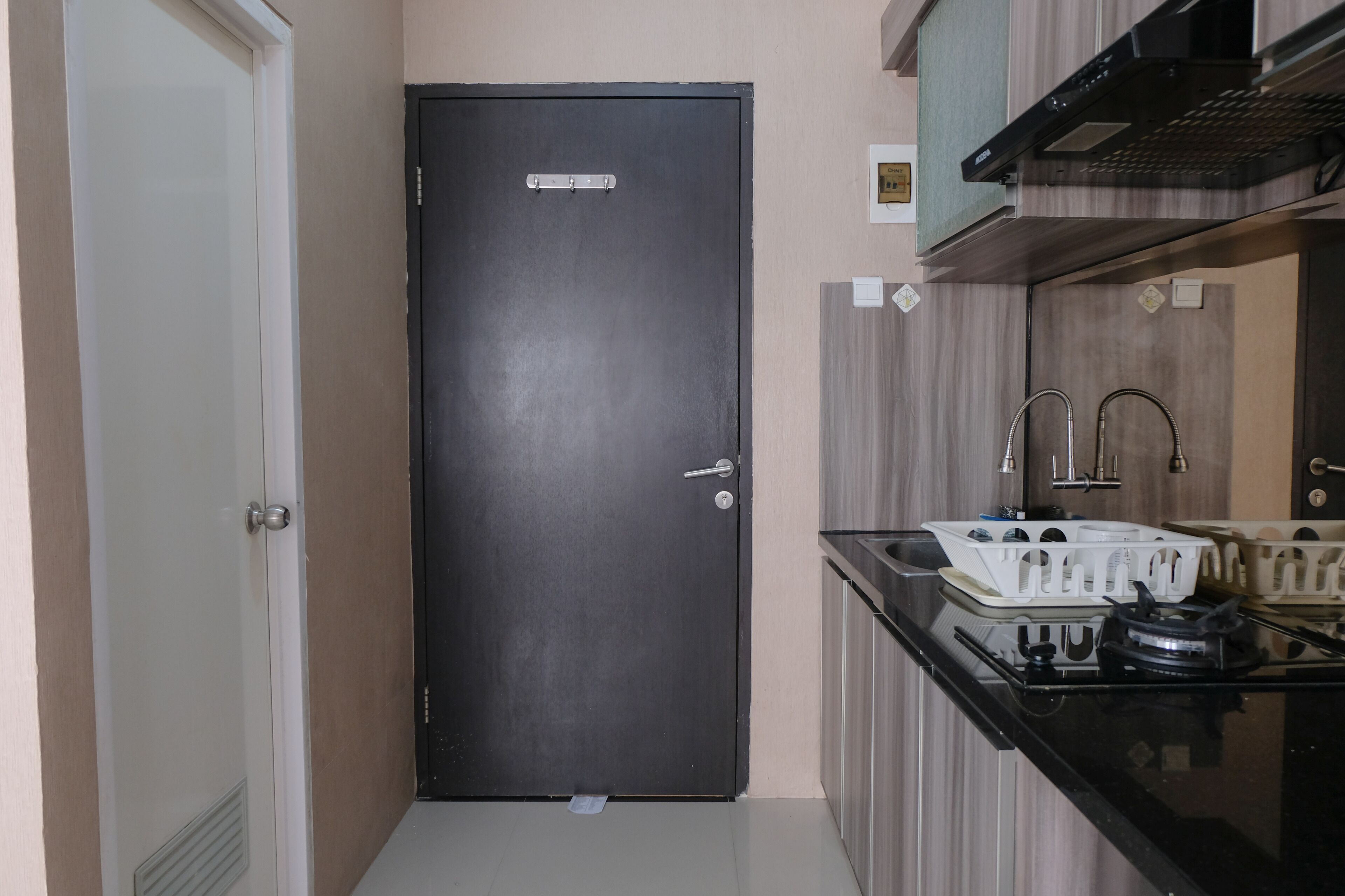 Une cuisine de taille réduite avec une porte noire, une cuisinière à gaz et un évier.