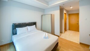 Une chambre d’hôtel avec un lit bien fait, une armoire et une porte donnant sur une autre pièce.