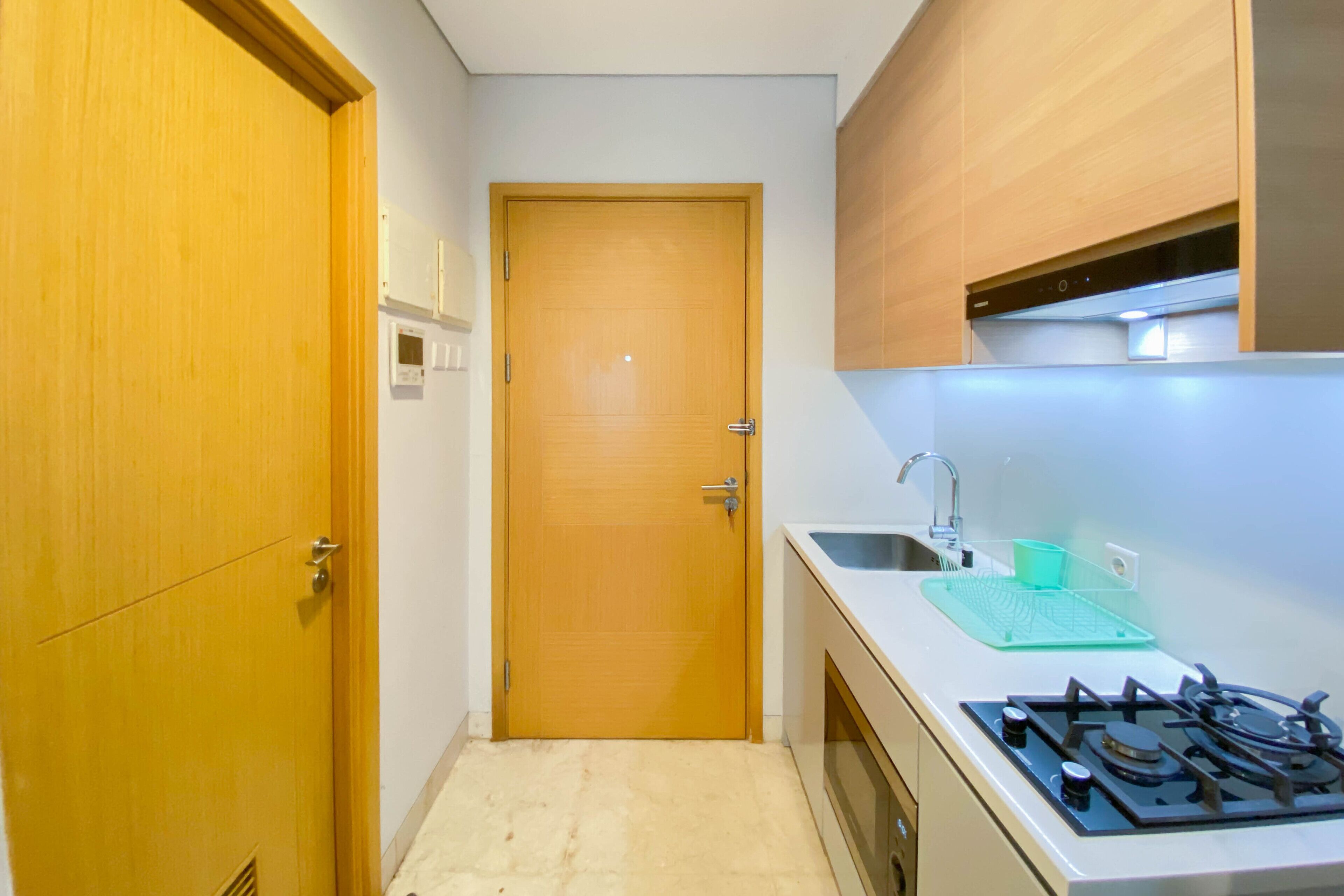 Una cocina pequeña con puerta de madera, un lavamanos y una estufa.
