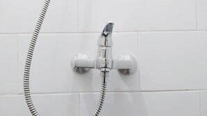 Un cabezal de ducha cromado con una manguera flexible conectada a un grifo de pared.
