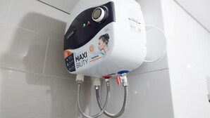 Un calentador de agua instalado en la pared, con un panel de control y dos mangueras flexibles.
