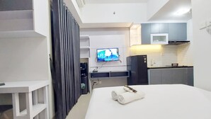 Una camera d'albergo moderna con un letto, una TV, una scrivania e angolo cottura.