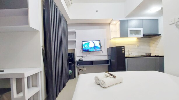 Una habitación de hotel moderna con cama, televisión, escritorio y kitchenette.