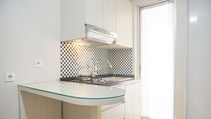 A compact kitchen with a glass countertop, a modern stove, and a checkered backsplash.