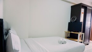 Ein Hotelzimmer mit Bett, Fernseher auf einem Schrank und einem Kleiderschrank.
