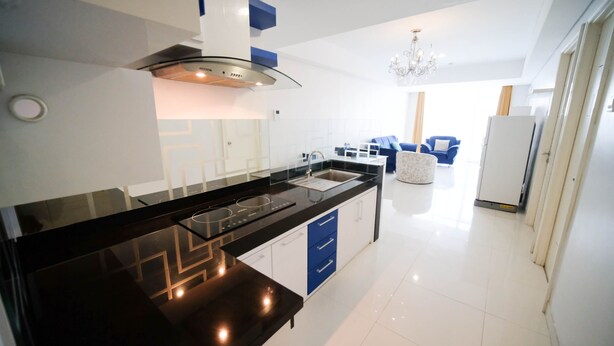 A modern kitchen with a black countertop, stainless steel sink, and a built-in range hood.