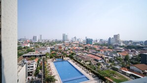 A residential area with a swimming pool, surrounded by houses and buildings, under a clear sky.