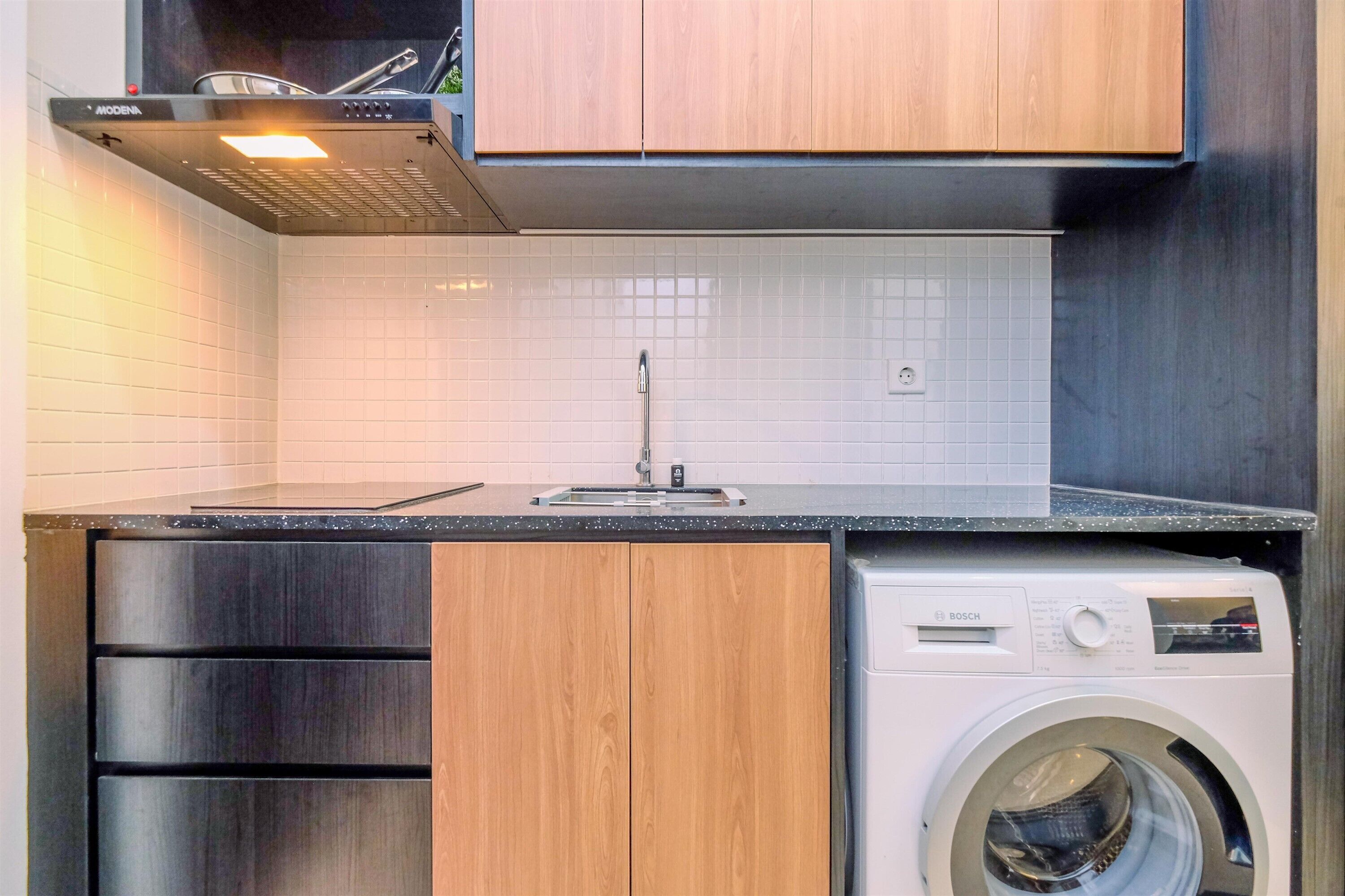 Una cocina moderna con armarios de madera, lavavajillas de acero inoxidable y lavadora Bosch.