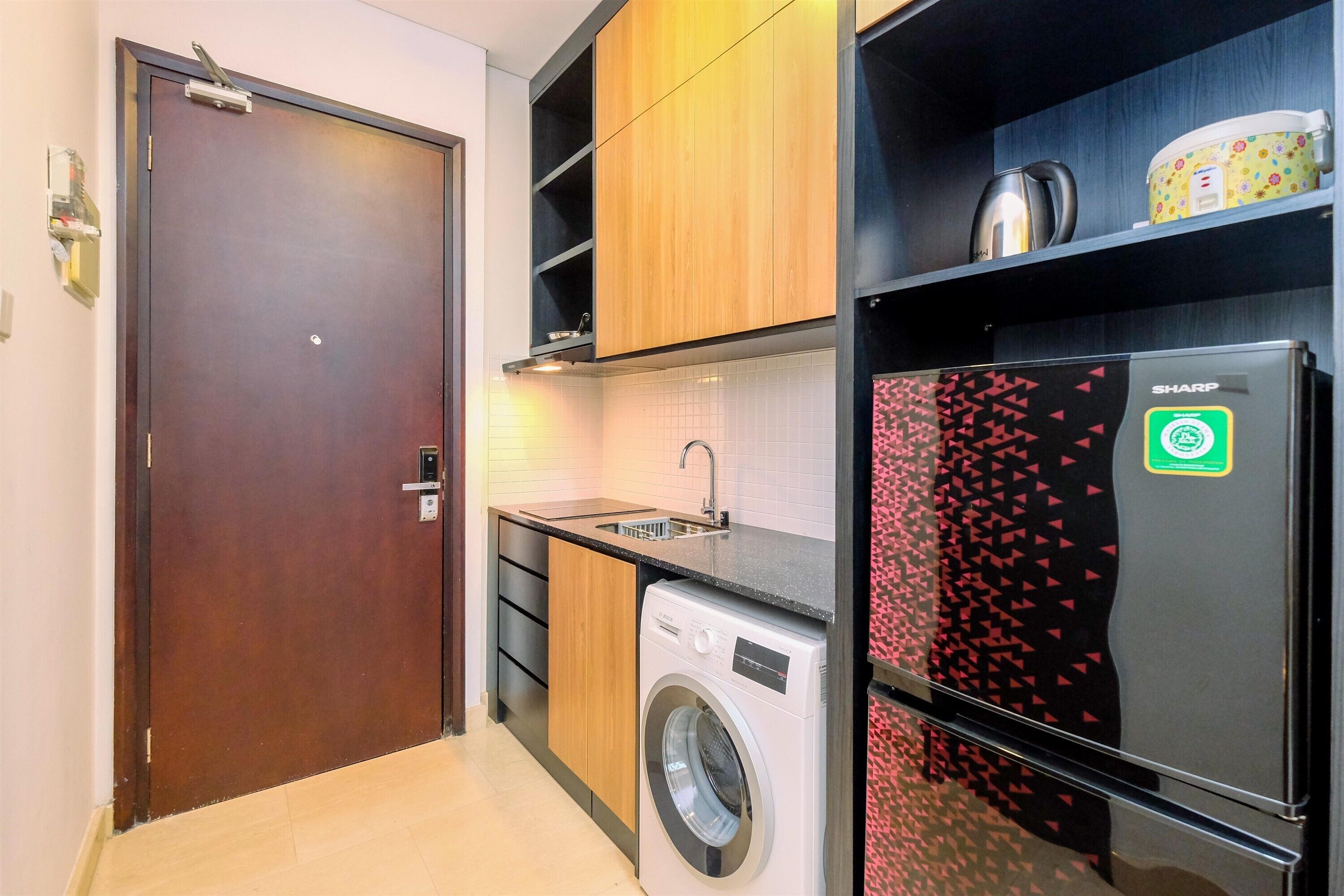 Una cocina funcional con lavadora, refrigerador y armarios de madera.
