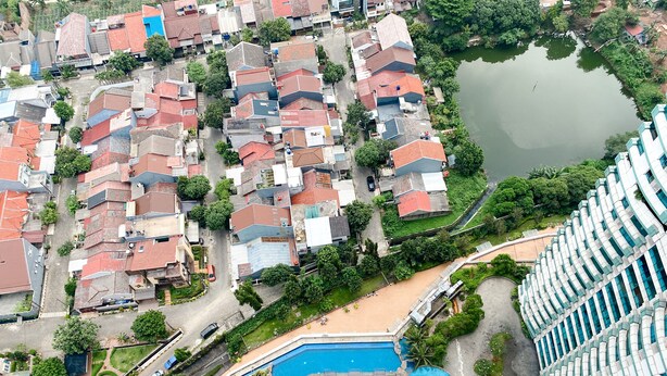 Una vista aerea di una zona residenziale con case, una piscina e una vasta distesa d'acqua.