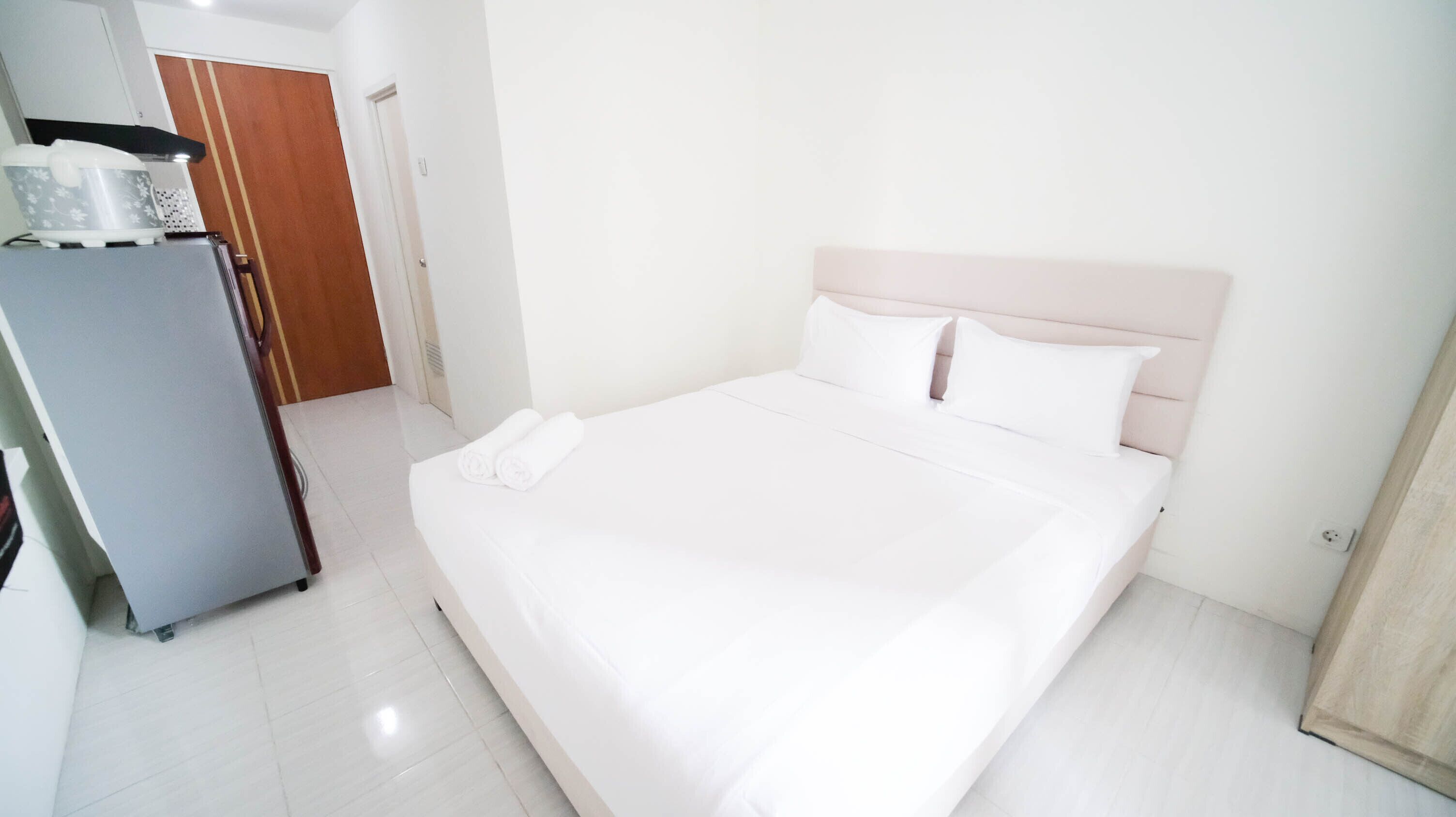 Una habitació d'hotel moderna i neta, amb un llit gran, roba de llit blanca i una petita zona de cuina.