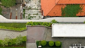 A rooftop garden with green plants and a grey wall. - Comfort And Minimalist Studio Menteng Park Apartment (Jakarta)