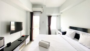 Una habitación de hotel con cama, televisión, escritorio y ventana con cortinas.