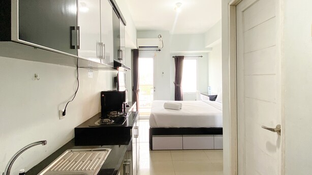 Una habitación de hotel pequeña con kitchenette, una cama y un baño.