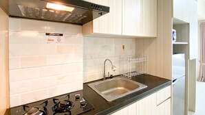 Uma cozinha moderna com armários brancos, bancada preta, pia de aço inoxidável e fogão a gás.