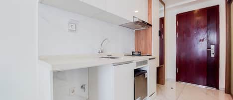 A modern kitchen with white cabinetry, a built-in oven, and a wooden door.