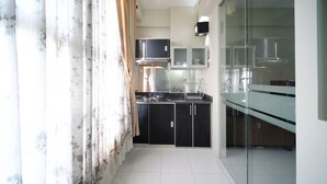 A modern kitchen with black cabinets, a stainless steel stove, and a glass backsplash. - Simple And Homey 2Br At Dian Regency Apartment (Surabaya)