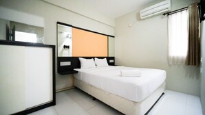 A hotel room with a bed, a nightstand, a mirror, and an air conditioning unit. - Simple And Homey 2Br At Dian Regency Apartment (Surabaya)