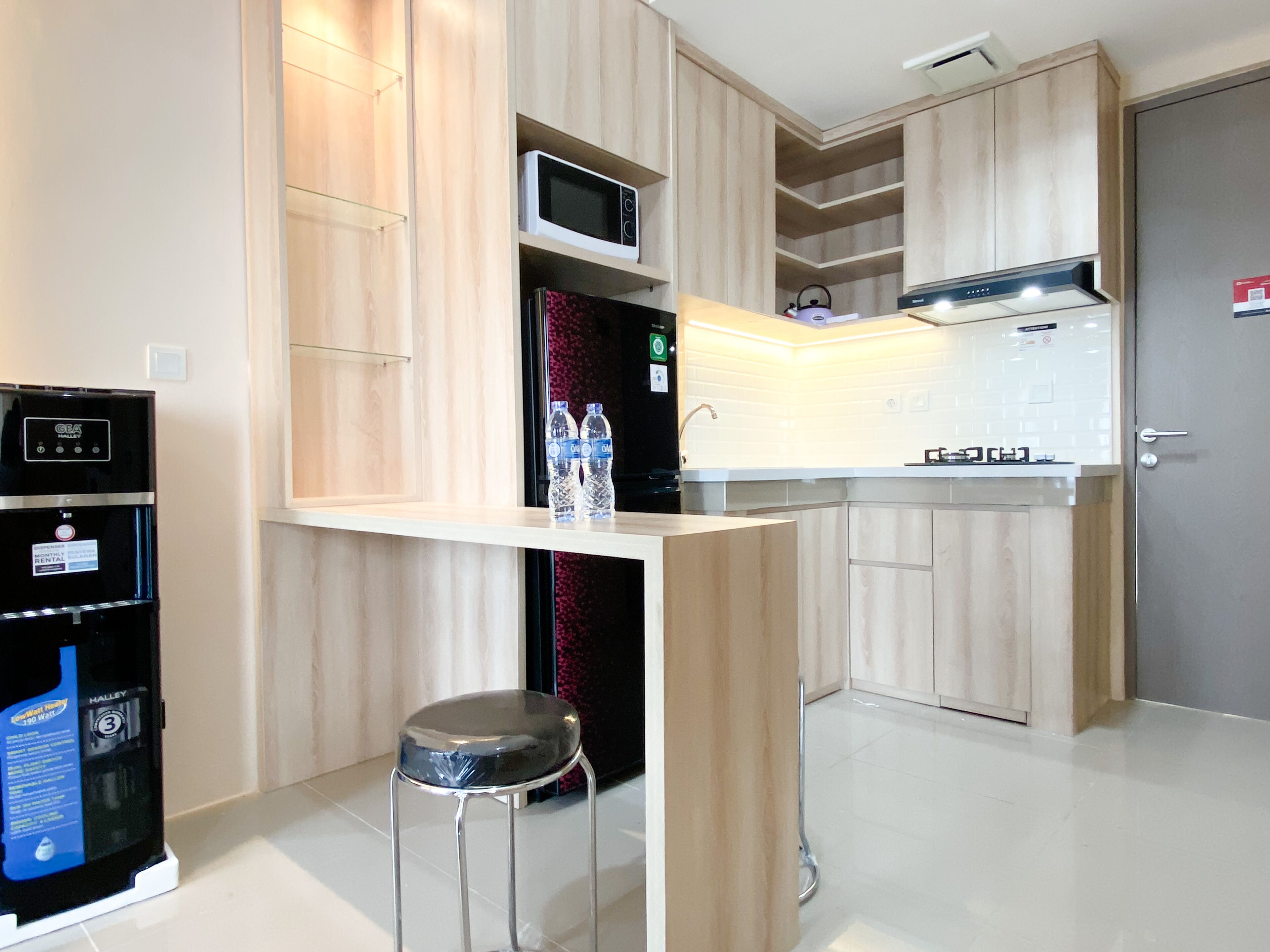 Une cuisine moderne dotée de meubles en bois, d’un four à micro-ondes, d’une cuisinière à gaz et d’un distributeur d’eau.