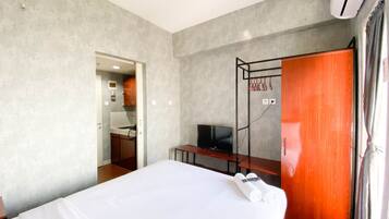 A hotel room with a bed, a TV, a wardrobe, and a small kitchenette.