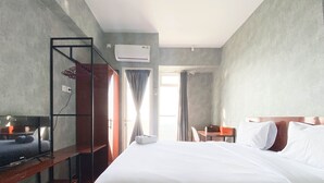 A hotel room with a large bed, a desk, a chair, a wardrobe, and a window with curtains. - Homey And Good Choice Studio At Amartha View Apartment (Semarang)