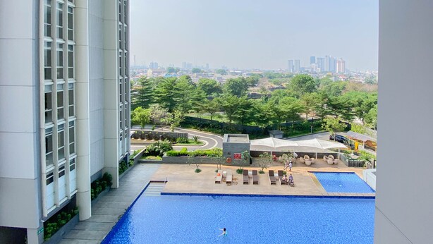 A rooftop pool with a view of a cityscape, surrounded by greenery and a covered seating area. - Cozy And Minimalist Studio Room Ciputra International Apartment (Jakarta)