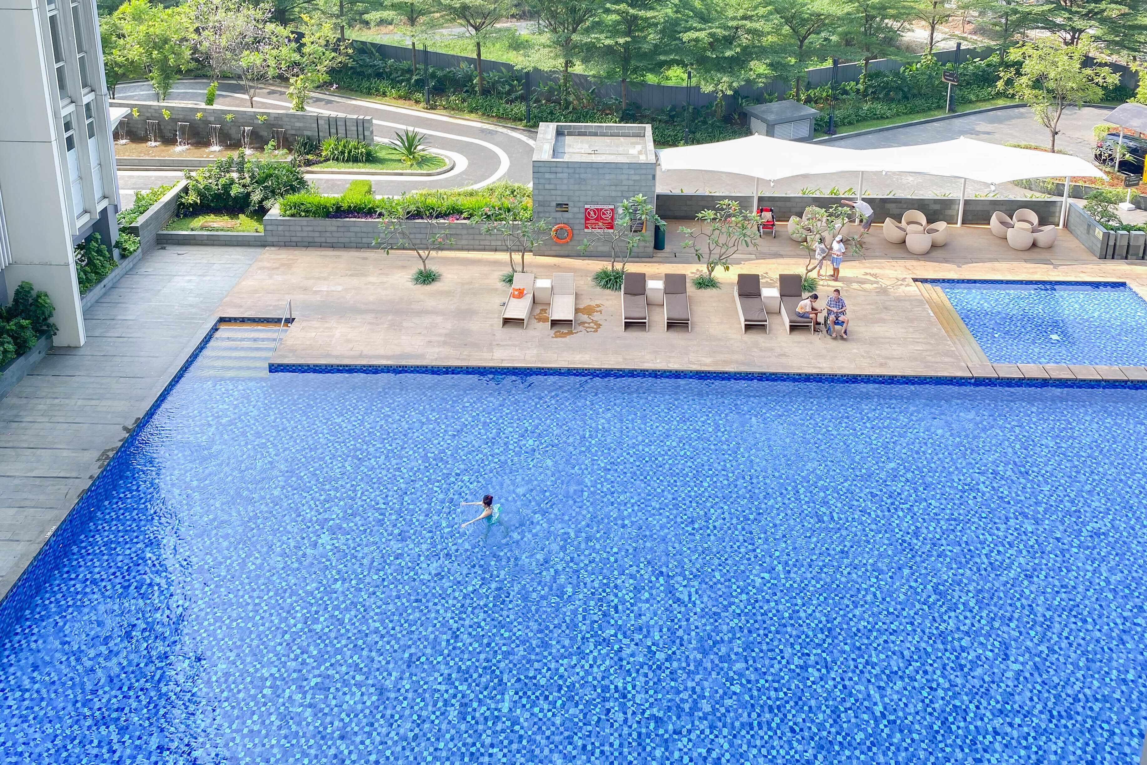 A swimming pool with lounge chairs and a covered seating area.