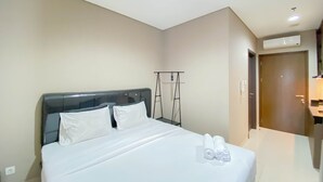 A neatly made bed with white linens, a headboard, and a pair of rolled towels on the foot of the bed. - Cozy And Minimalist Studio Room Ciputra International Apartment (Jakarta)