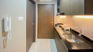 A modern kitchen with a built-in sink, a white telephone, and an air conditioning unit above the door. - Cozy And Minimalist Studio Room Ciputra International Apartment (Jakarta)