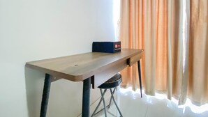 A wooden table with a box on it, positioned against a white wall with a window and curtains. - Cozy And Minimalist Studio Room Ciputra International Apartment (Jakarta)