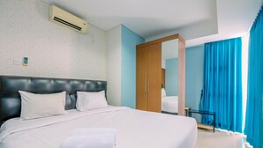 Ein Hotelzimmer mit einem großen Bett, einem Holzschrank, einem Spiegel und einem Fenster mit blauen Vorhängen.