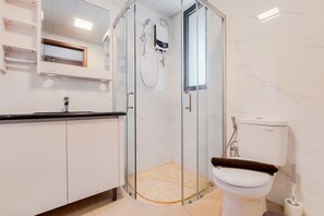 A modern bathroom with a glass-enclosed shower, a white toilet, and a marble-tiled wall. - Comfort And Spacious 3Br At Sky House Bsd Apartment (Pagedangan)
