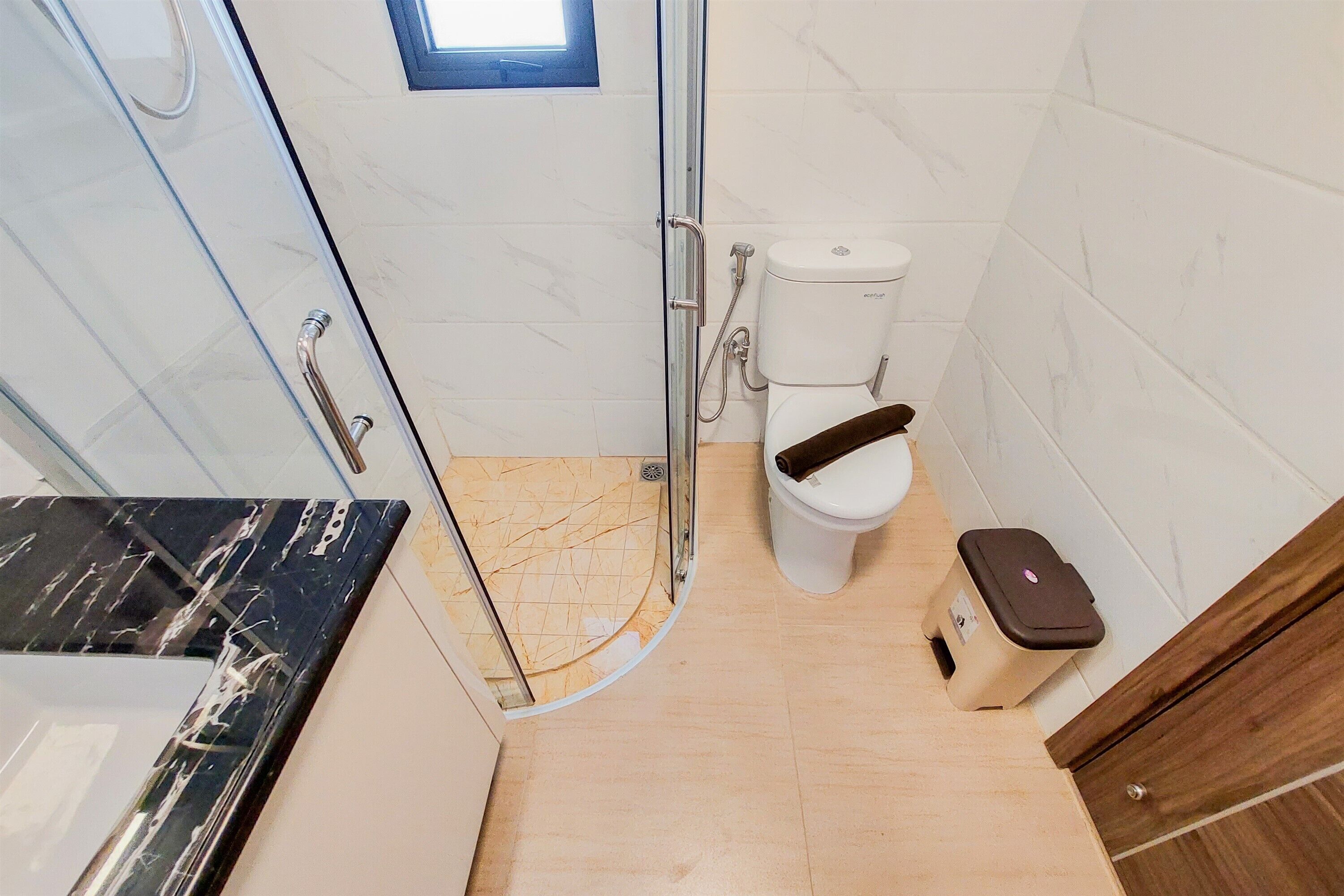 Un baño con inodoro, ducha y cubo de basura.