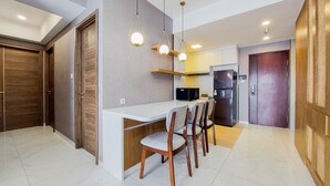 A modern kitchen with a white countertop, wooden chairs, and pendant lights. - Comfort And Spacious 3Br At Sky House Bsd Apartment (Pagedangan)