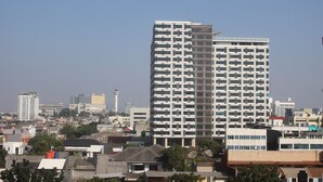 Ein Hochhaus mit einer rasterförmigen Fassade, umgeben von weiteren Gebäuden und Bäumen.