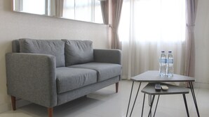 Ein graues Sofa mit einem kleinen Tisch, zwei Wasserflaschen und einer Fernbedienung.