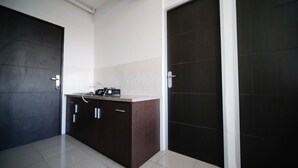 A modern kitchen with dark wooden cabinets, a white countertop, and a stainless steel sink. - Simple 2Br With Extra Bed At Menara Rungkut Apartment (Surabaya)